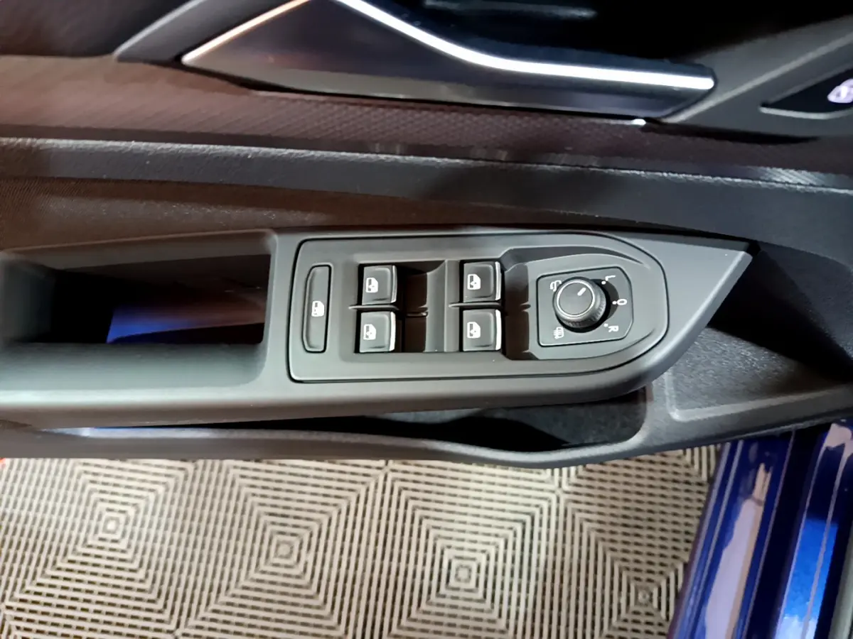 Vue rapprochée du panneau de commandes des vitres et rétroviseurs côté conducteur d'une Volkswagen Golf bleue 2022.