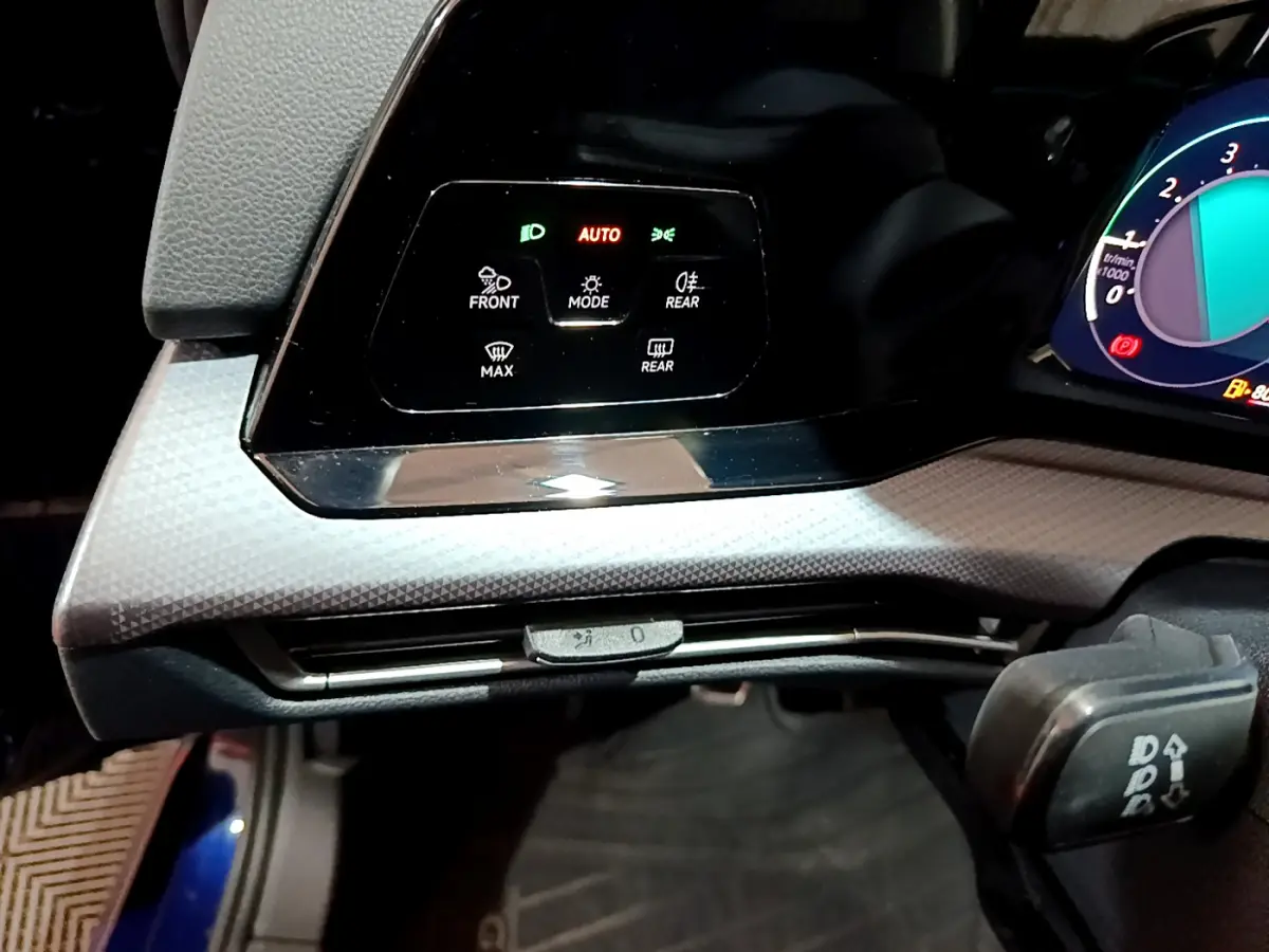 Détail du panneau de commande d'éclairage avec affichage digital sur tableau de bord d'une Volkswagen Golf bleue 2022.