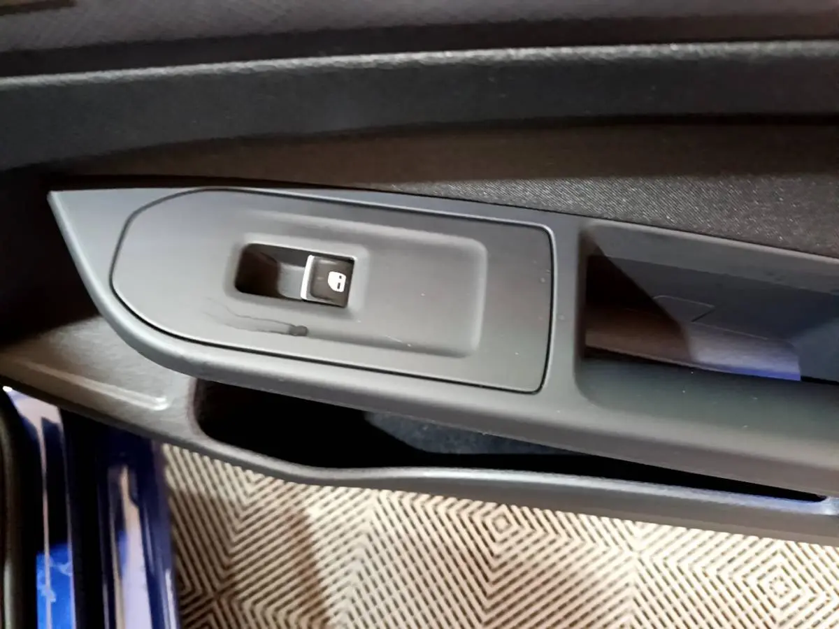 Gros plan sur la commande de verrouillage des portes côté conducteur d'une Volkswagen Golf bleu 2022.