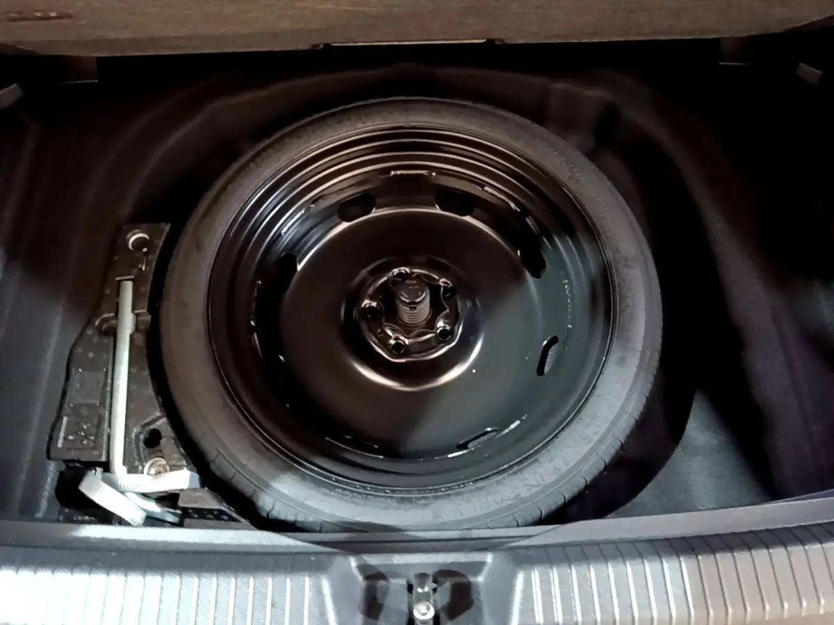 Gros plan sur la roue de secours noire dans le coffre d'une Volkswagen Golf 1.0 TSI bleu 2022.