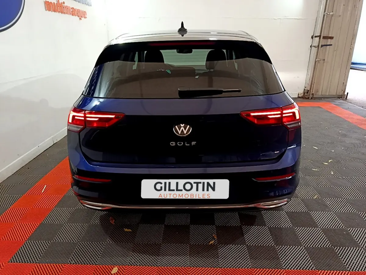 Vue arrière d'une Volkswagen Golf bleu 2022 avec feux LED allumés et logo VW visible sur le hayon.