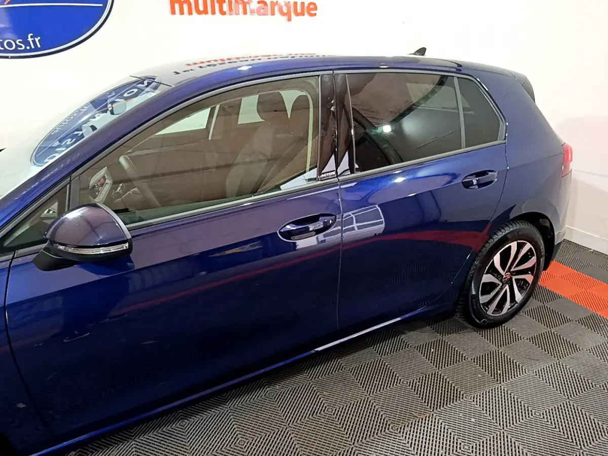 Vue latérale côté gauche d'une Volkswagen Golf 1.0 TSI Active bleu avec jantes alliage et vitres teintées.