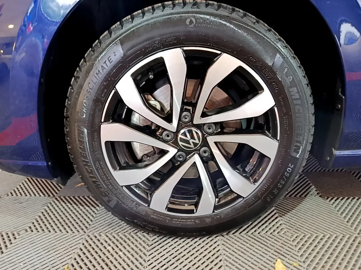 Gros plan sur la roue avant gauche d'une Volkswagen Golf bleu 2022 avec jante alliage bicolore et pneu Michelin.