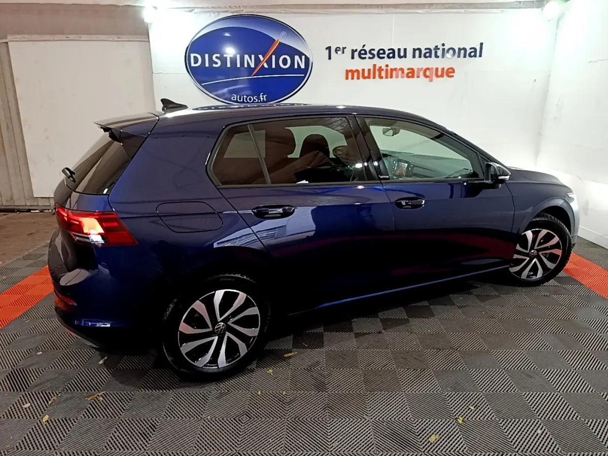 Volkswagen Golf 1.0 TSI bleu vue de profil côté gauche dans un showroom avec logo Distinxion en arrière-plan