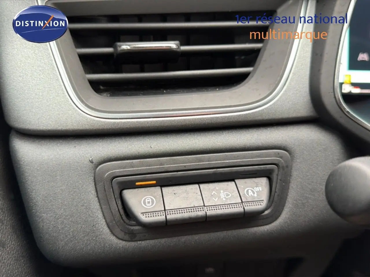 Détail des commandes de réglage des phares et verrouillage sur le tableau de bord du Renault Captur bleu Iron Metal 2025.