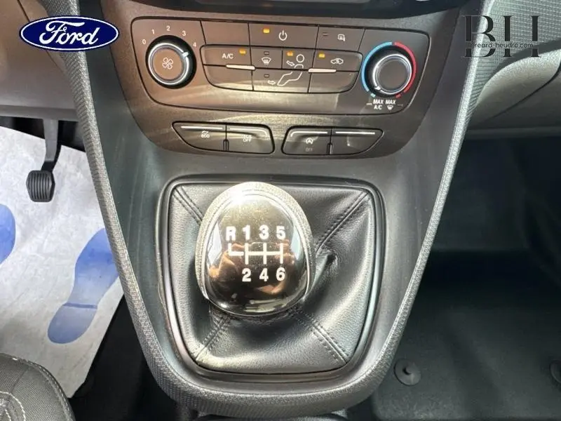 Gros plan sur la commande de boîte manuelle et la console centrale du Ford Transit Connect noir avec climatisation et commandes visibles.