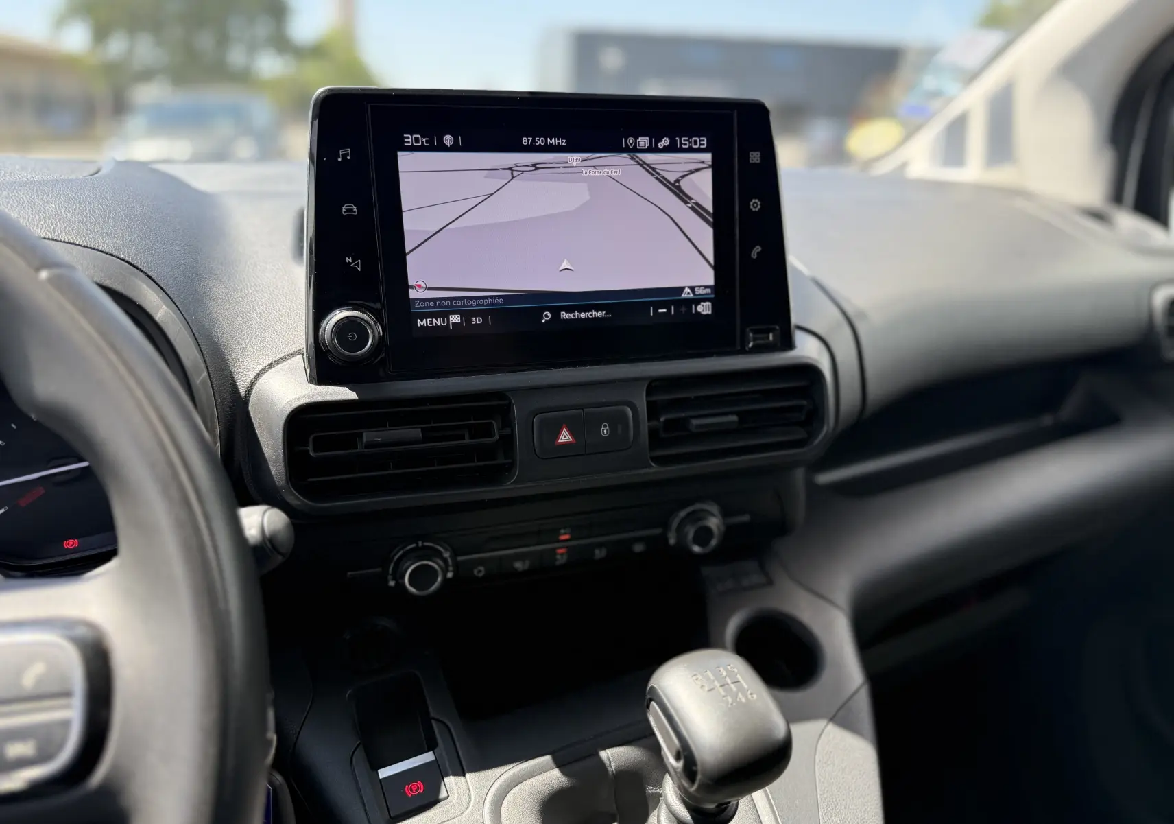 Vue intérieure centrée sur la console centrale du Citroën Berlingo XL blanc banquise avec écran tactile et levier de vitesse manuel.