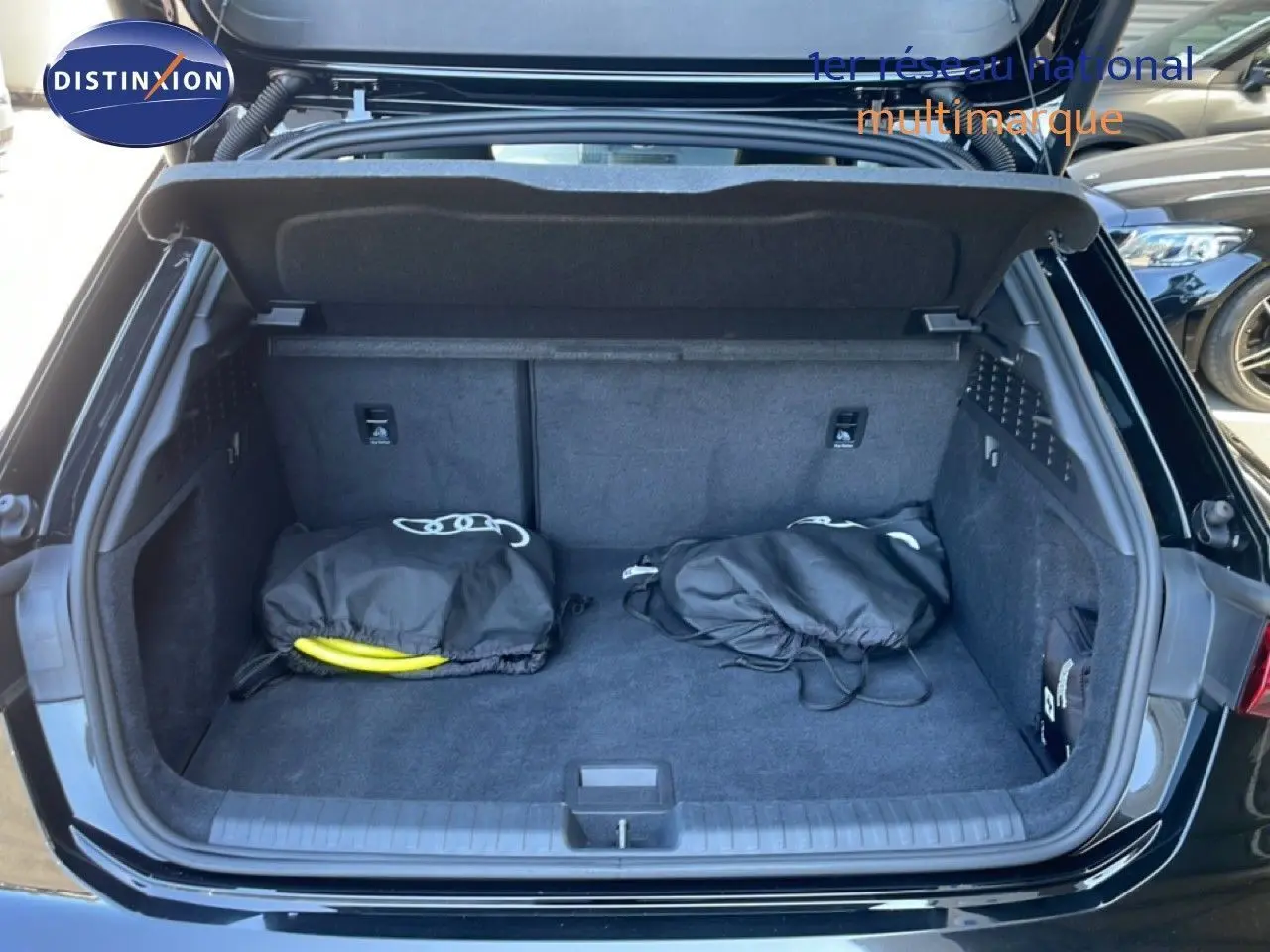 Coffre ouvert vu de l'arrière d'une Audi A3 Sportback noire 2025, montrant un intérieur de coffre propre avec deux sacs noirs.