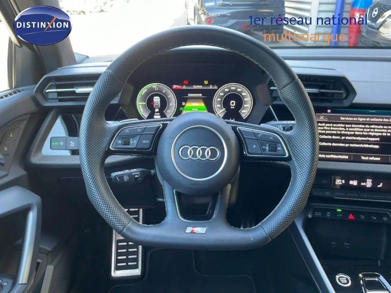 Vue intérieure centrée sur le volant noir perforé de l'Audi A3 Sportback 2025 avec tableau de bord numérique et écran tactile.
