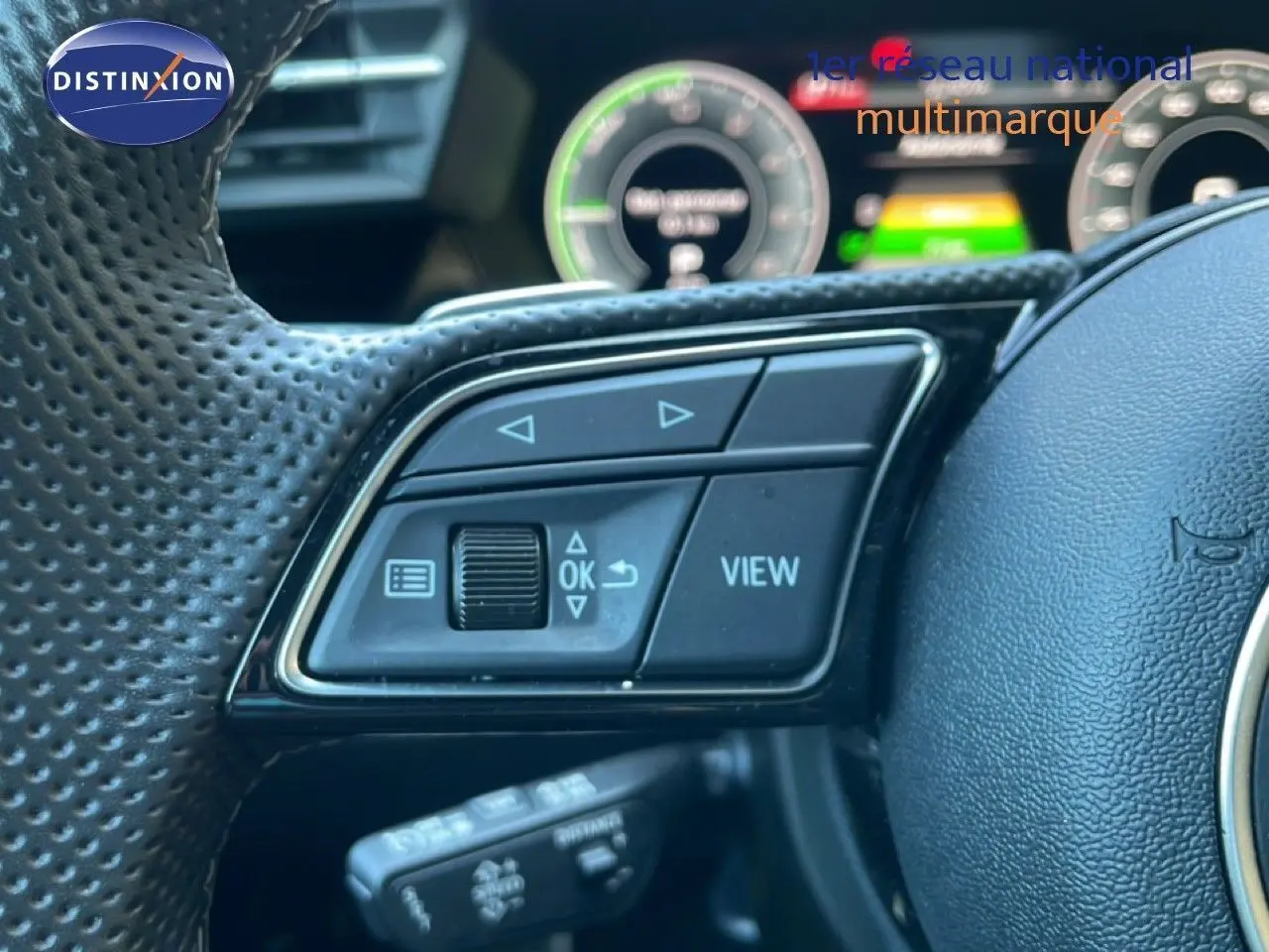 Gros plan sur les commandes gauche du volant noir perforé d’une Audi A3 Sportback hybride rechargeable 2025.