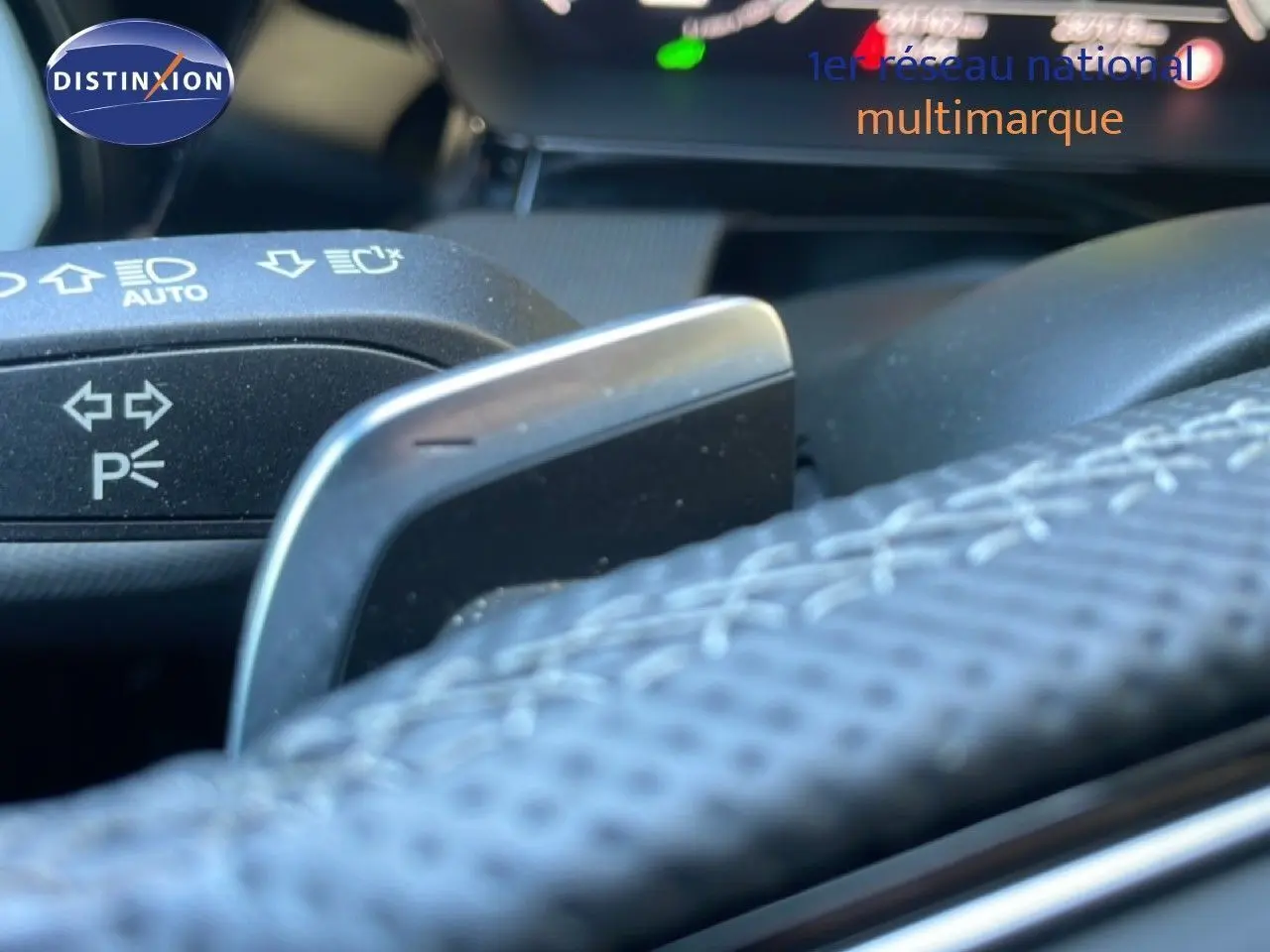 Gros plan sur la palette de changement de vitesse derrière le volant cuir perforé d’une Audi A3 Sportback noire hybride rechargeable.