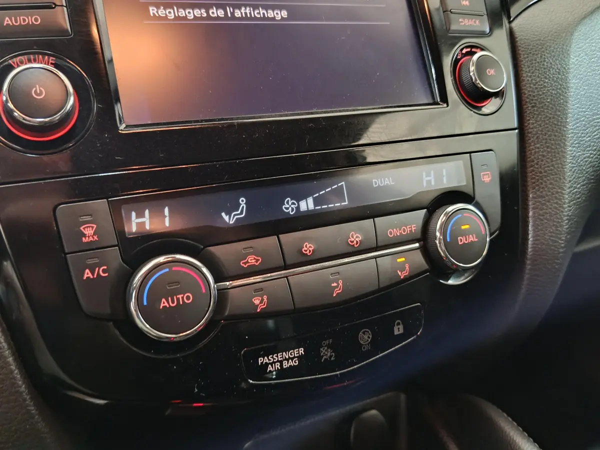 Gros plan sur la console centrale noire du Nissan Qashqai 2019, montrant les commandes de climatisation digitale bi-zone.