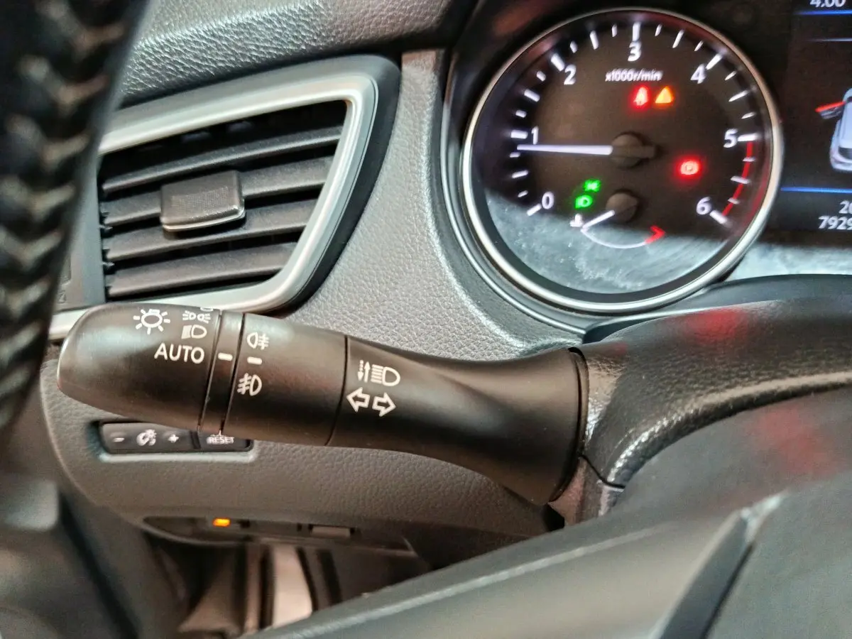 Gros plan sur la commande des feux et clignotants à gauche du volant du Nissan Qashqai gris clair 2019, tableau de bord visible.