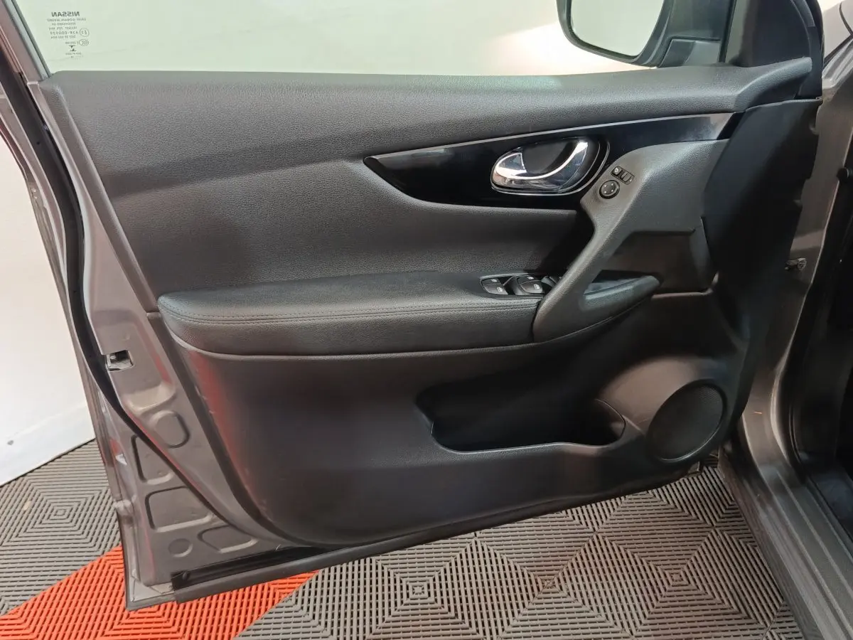 Porte avant gauche ouverte d'un Nissan Qashqai gris clair 2019, montrant la garniture intérieure noire et les commandes électriques.