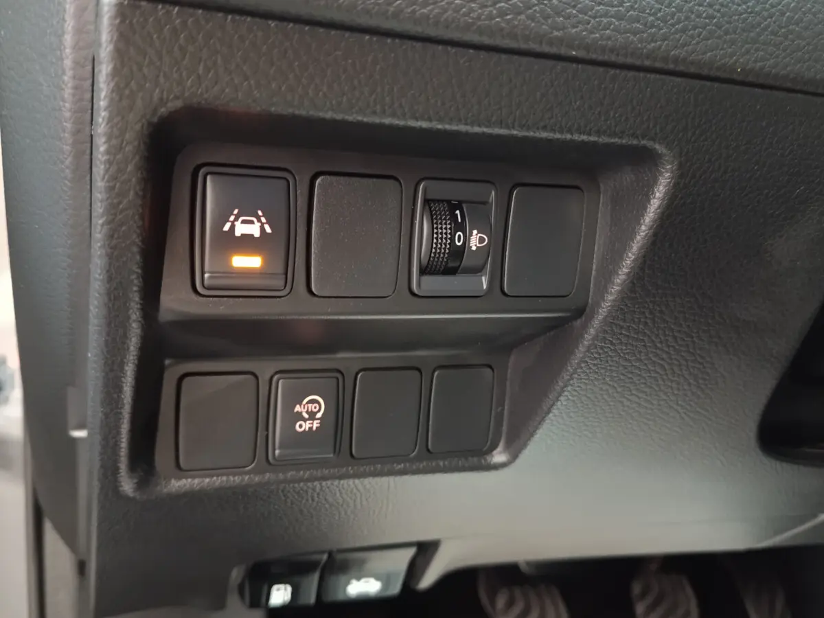 Gros plan sur les commandes d'assistance et réglage des phares du Nissan Qashqai gris clair, version 2019.