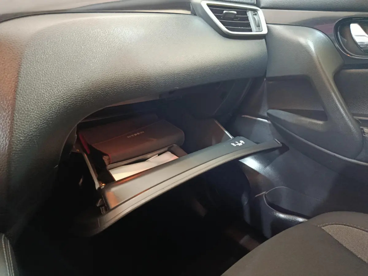 Intérieur du Nissan Qashqai 2019 montrant la boîte à gants ouverte côté passager avec manuel de bord visible.