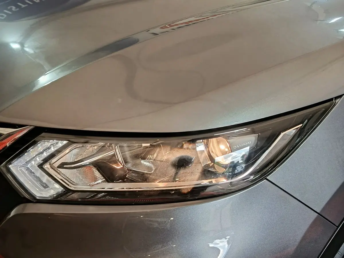 Gros plan sur le phare avant droit gris clair du Nissan Qashqai 2019 avec inscription "Qashqai" visible.