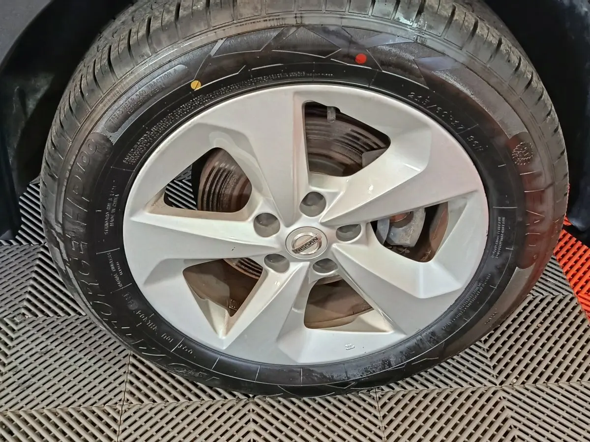 Gros plan sur la roue avant avec jante alliage argentée du Nissan Qashqai 2019 gris clair.