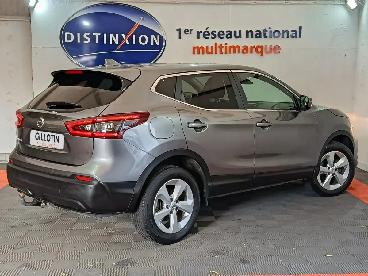 Nissan Qashqai gris clair vu de côté droit arrière, avec feux arrière allongés et jantes alliage cinq branches.