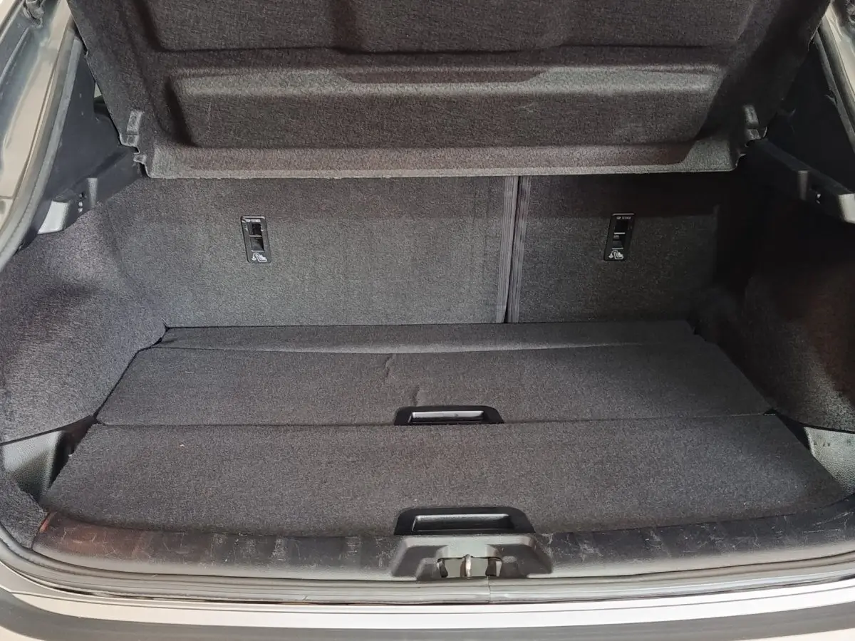 Coffre ouvert du Nissan Qashqai gris clair 2019, montrant l'espace de chargement avec tablette de séparation.