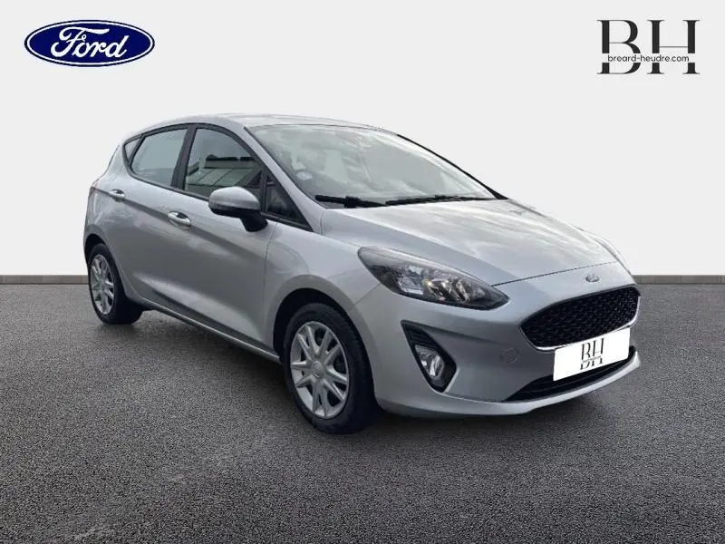 Vue 3/4 avant droite d'une Ford Fiesta gris lunaire 2021 avec calandre noire et jantes argentées.