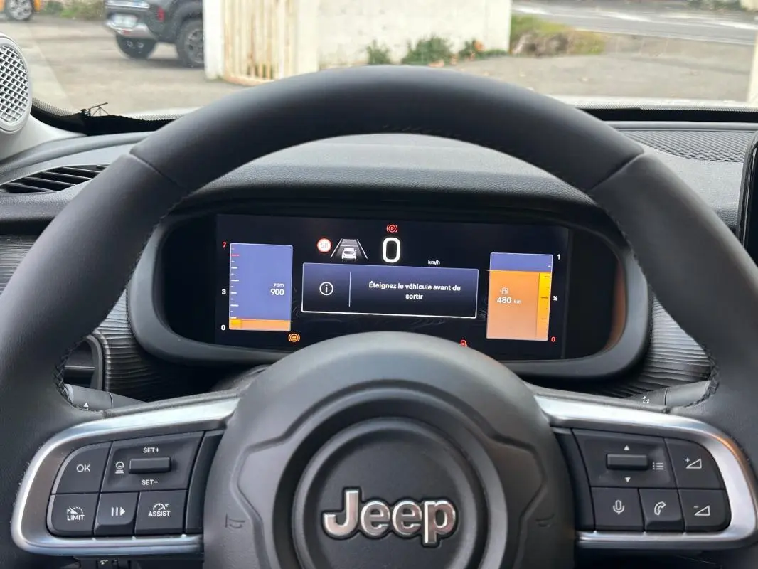 Vue intérieure centrée sur le volant Jeep noir avec tableau de bord numérique affichant 0 km/h et alertes.