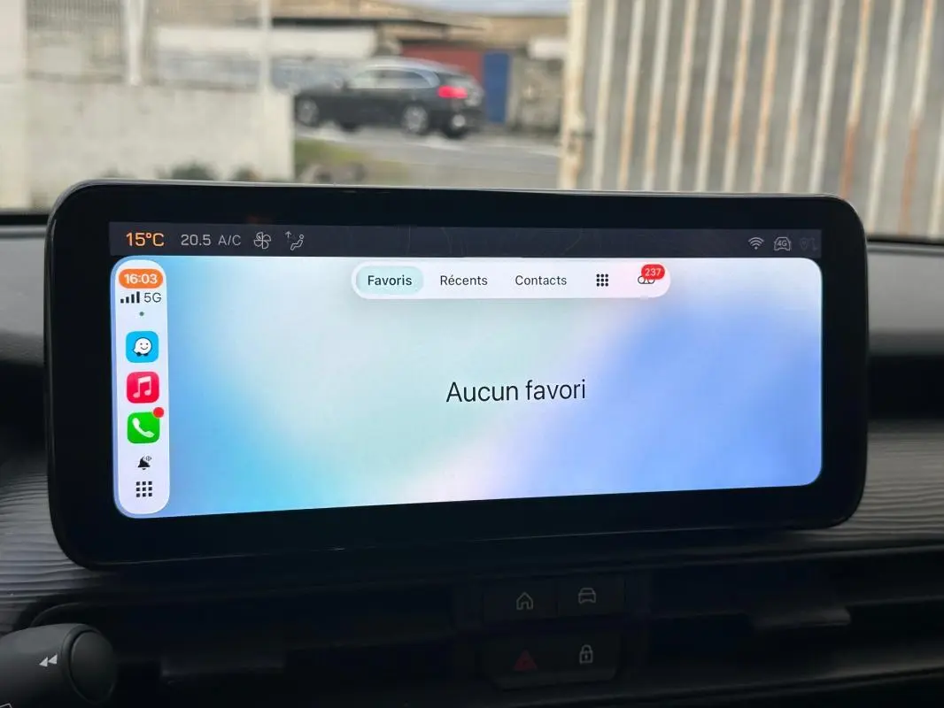 Écran tactile intérieur du Jeep Avenger 2024 affichant un menu de favoris, avec vue partielle du tableau de bord noir.