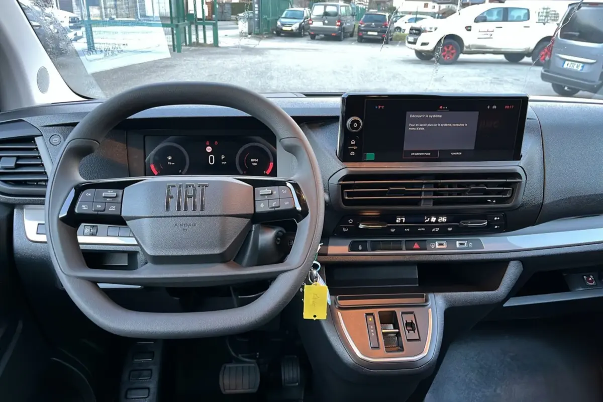 Vue intérieure frontale du tableau de bord noir du Fiat Scudo Fourgon 2025 avec volant multifonctions et écran tactile.