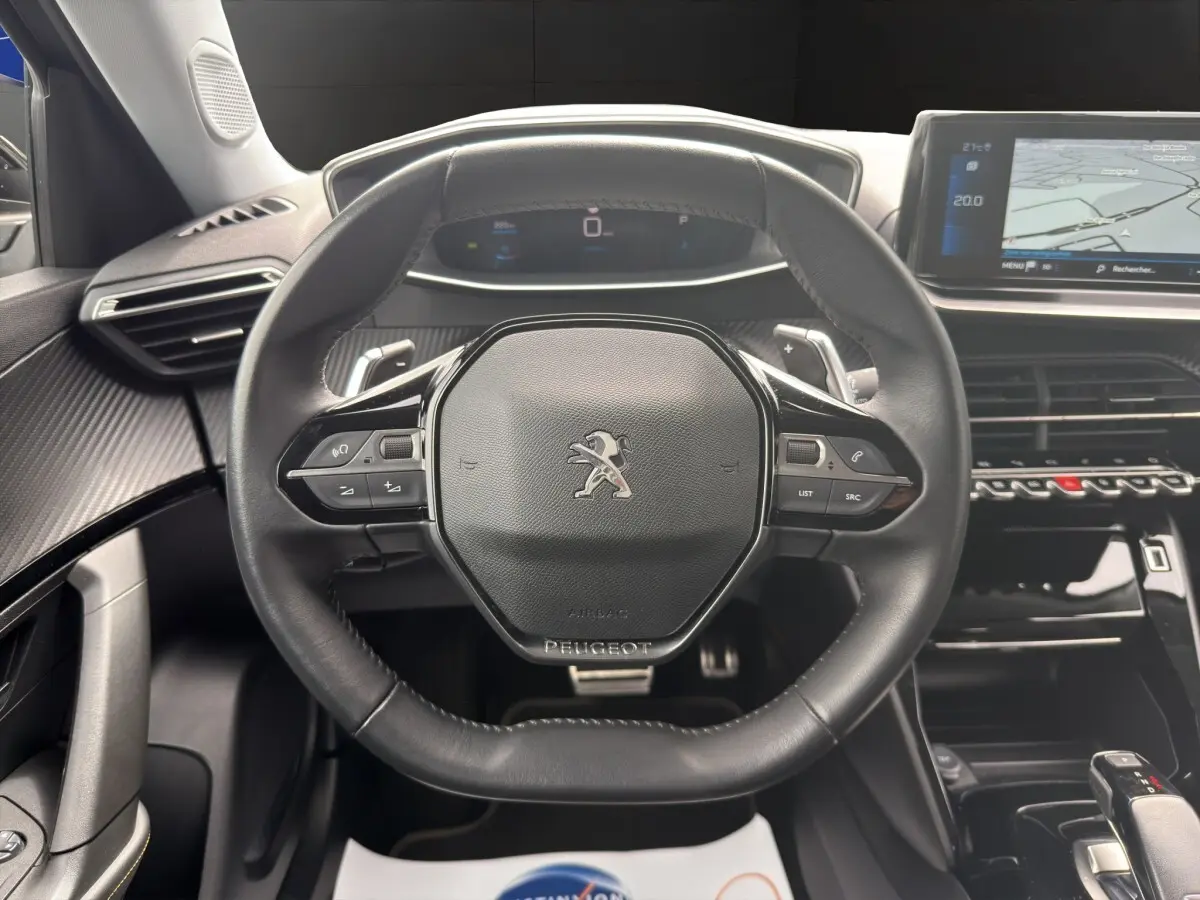 Vue centrée sur le volant cuir noir du Peugeot 2008 2022 avec tableau de bord digital et écran tactile de navigation.