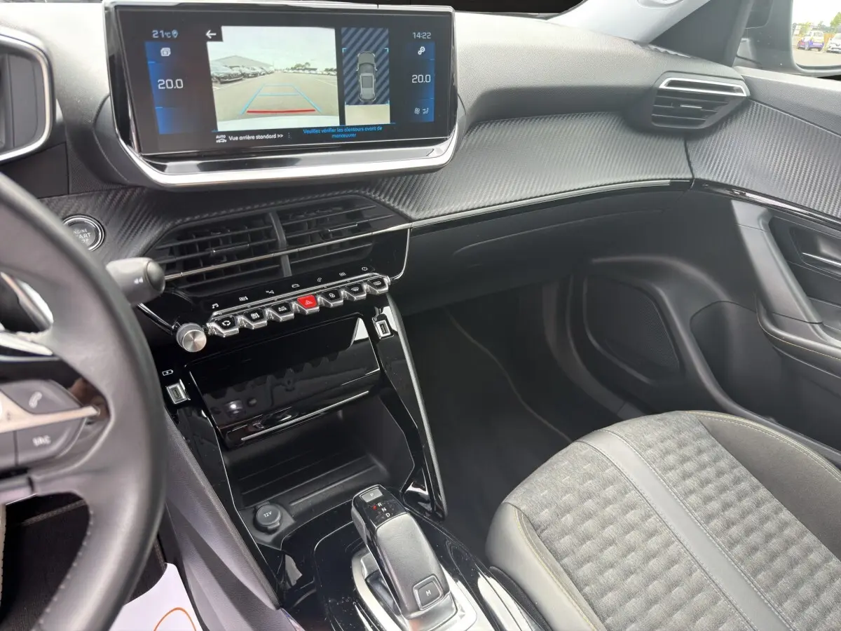 Vue intérieure côté passager du tableau de bord et console centrale noire brillante du Peugeot 2008 gris foncé 2022.