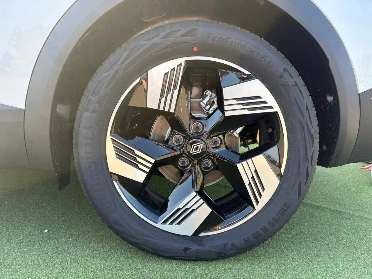 Gros plan sur la jante 18 pouces bicolore noire et argentée du Renault Symbioz blanc nacré, avec pneu Continental.