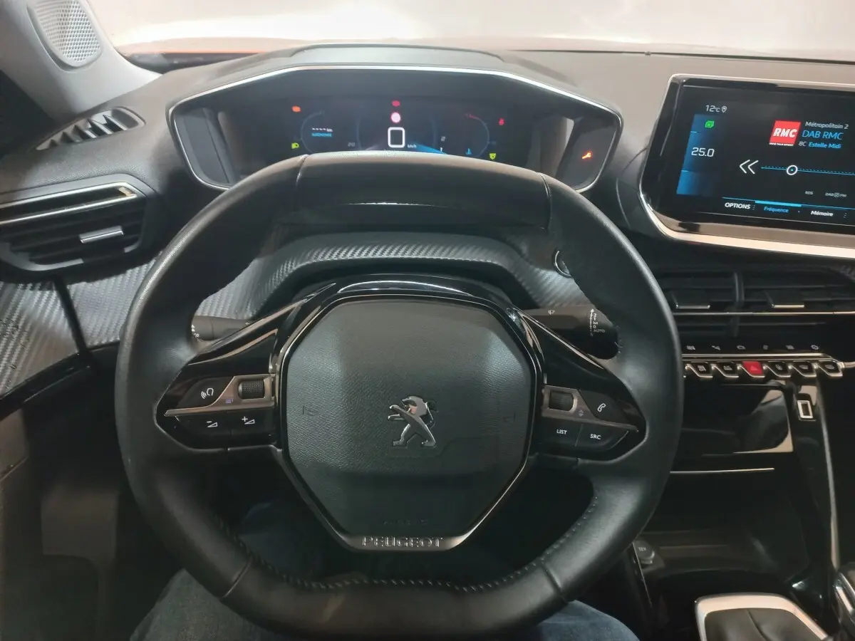 Vue intérieure centrée sur le volant cuir noir du Peugeot 2008 2021 avec tableau de bord numérique et écran tactile.