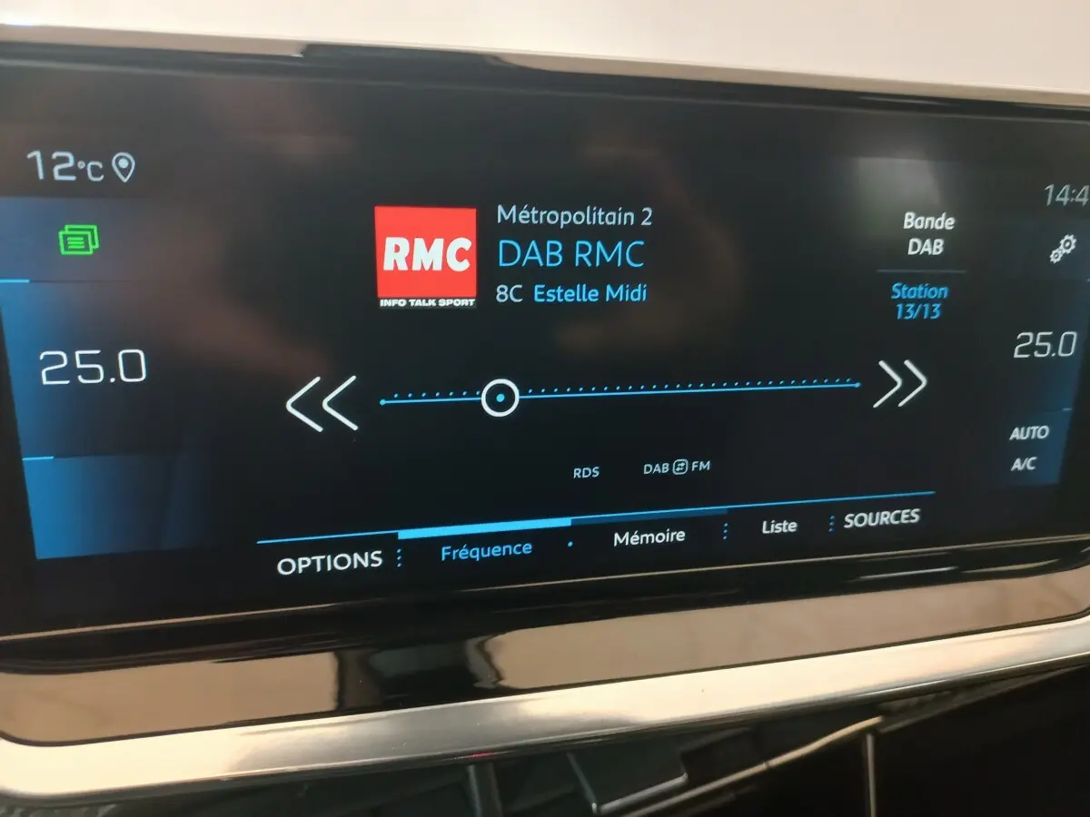 Écran tactile central du tableau de bord du Peugeot 2008 orange, affichant la radio DAB RMC et la climatisation à 25°C.