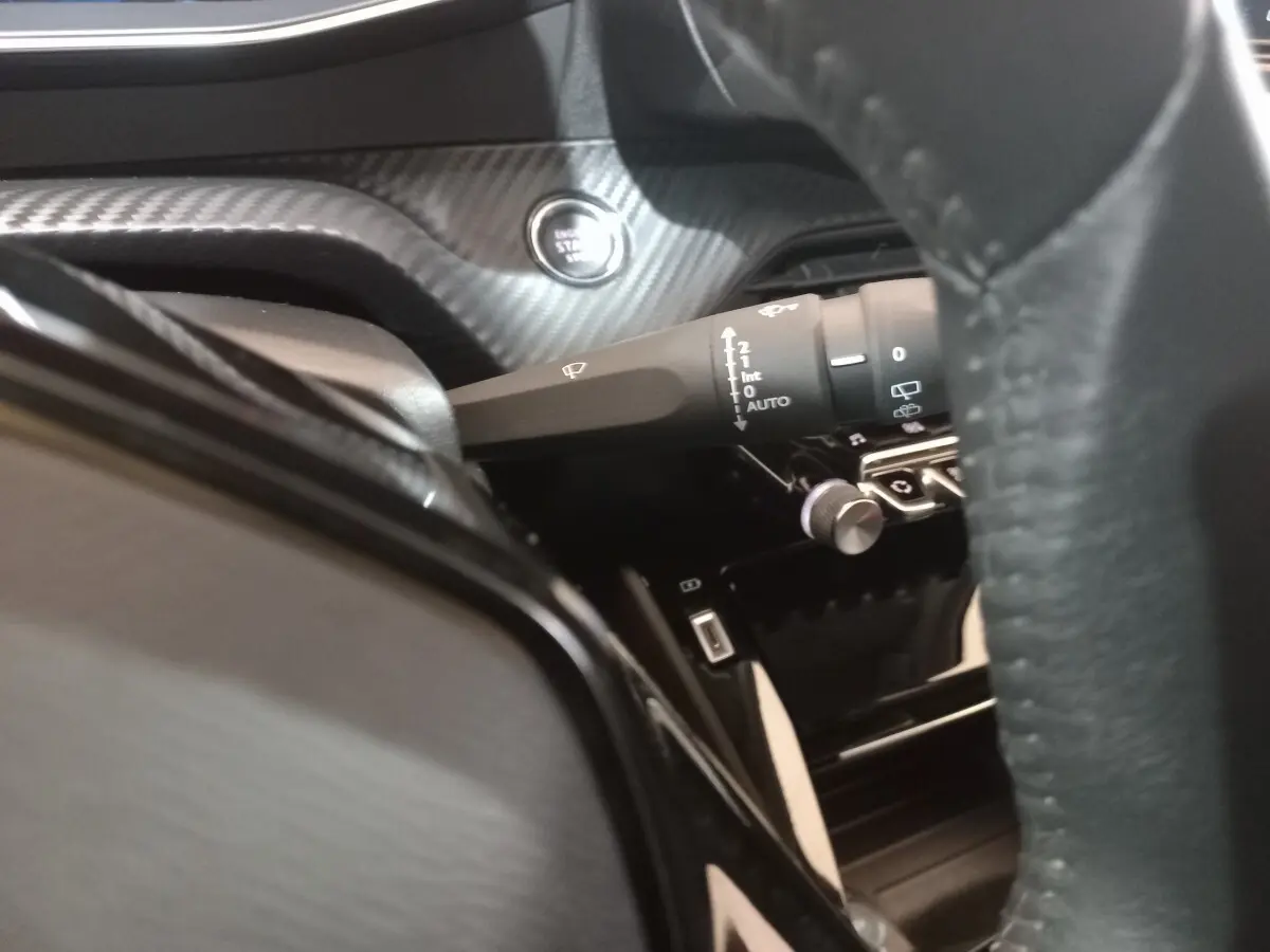Gros plan sur la commande d’essuie-glace et bouton démarrage dans l’habitacle noir du Peugeot 2008 orange.