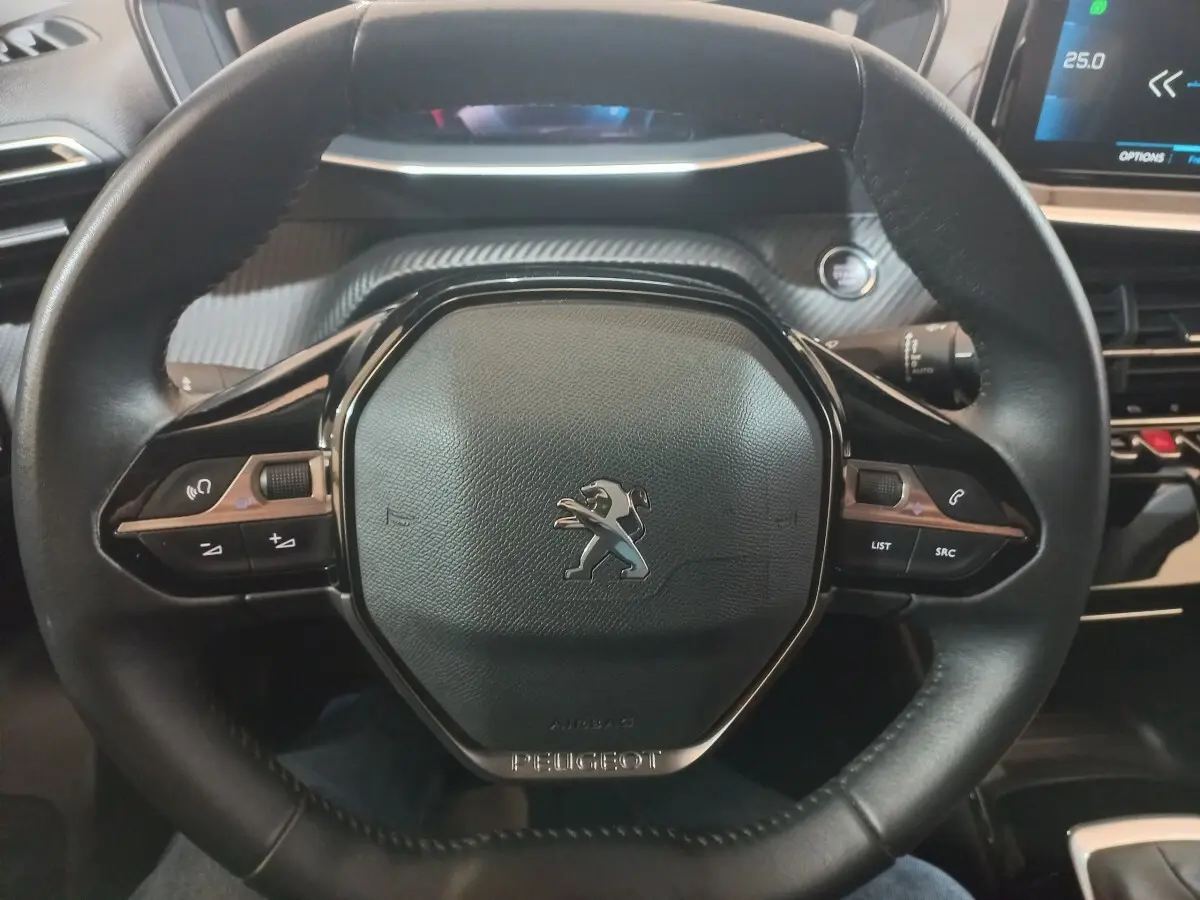 Volant cuir noir de Peugeot 2008 2021 avec commandes intégrées et tableau de bord numérique partiellement visible.