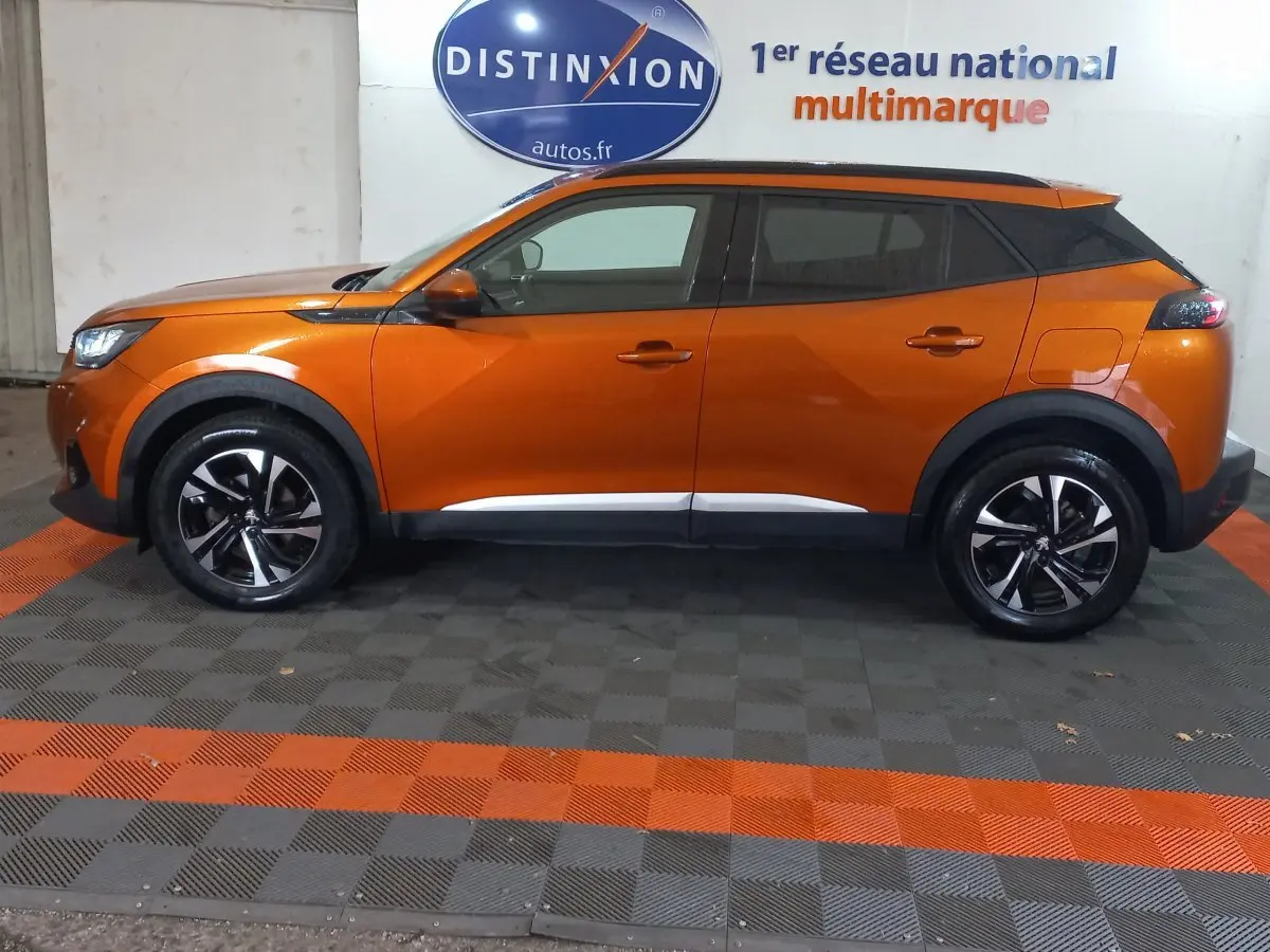 Profil côté gauche d'un Peugeot 2008 orange 2021, finition Allure Business, avec jantes noires et toit noir contrasté.