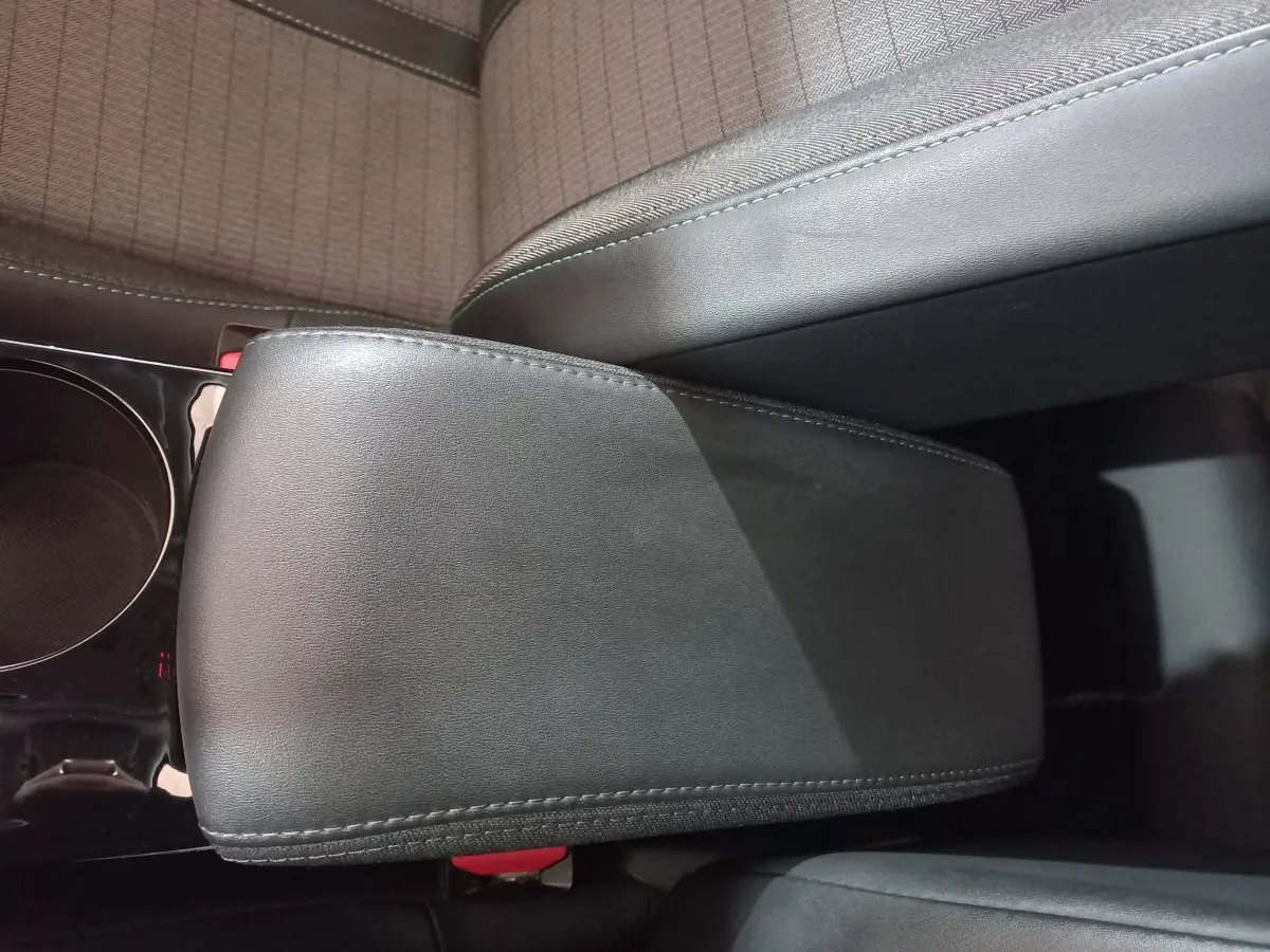 Accoudoir central noir en cuir dans l'habitacle du Peugeot 2008 Orange, vue plongeante sur les sièges avant.