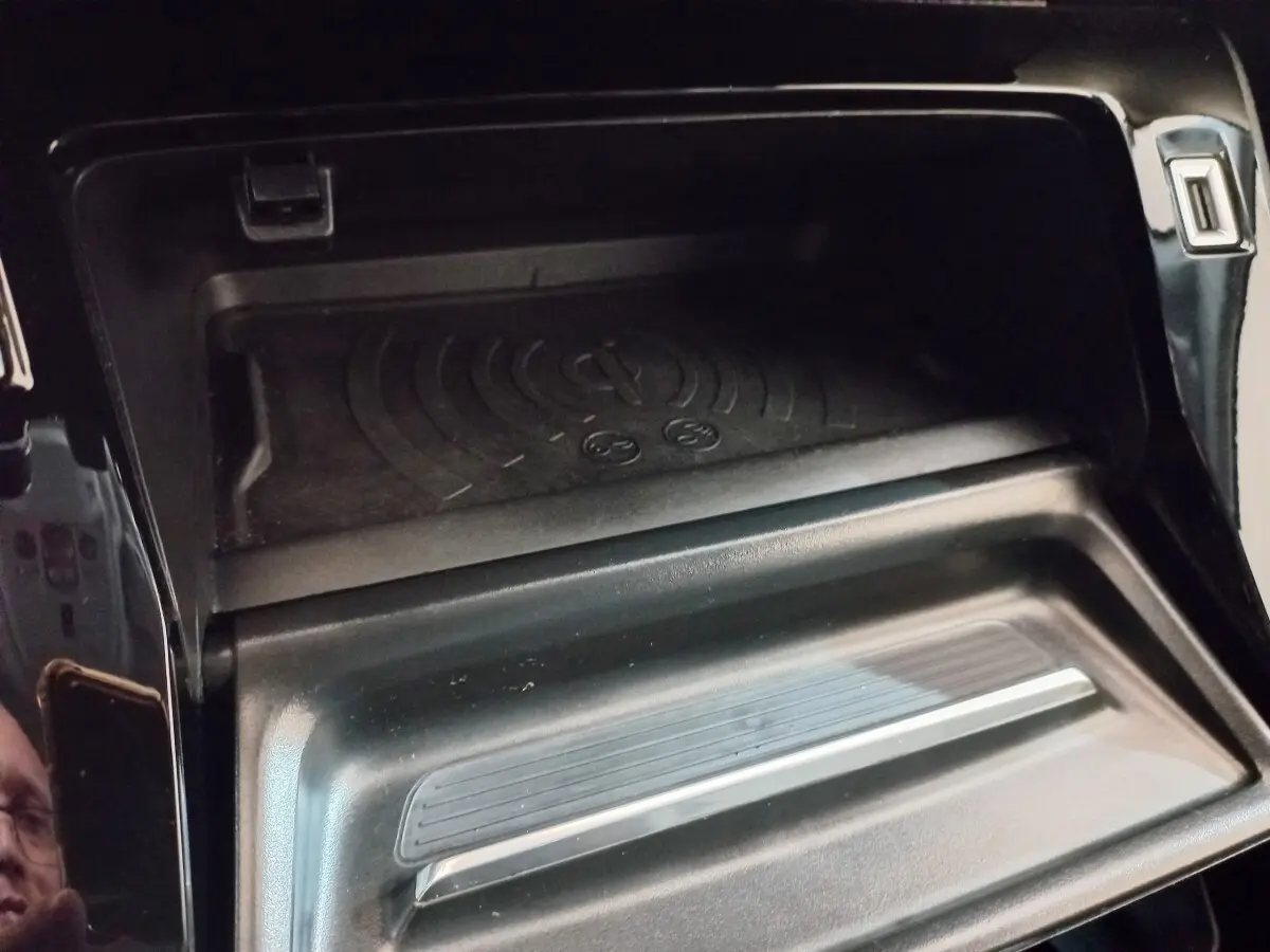 Gros plan sur la zone de recharge par induction noire dans l'habitacle du Peugeot 2008 Orange 2021.