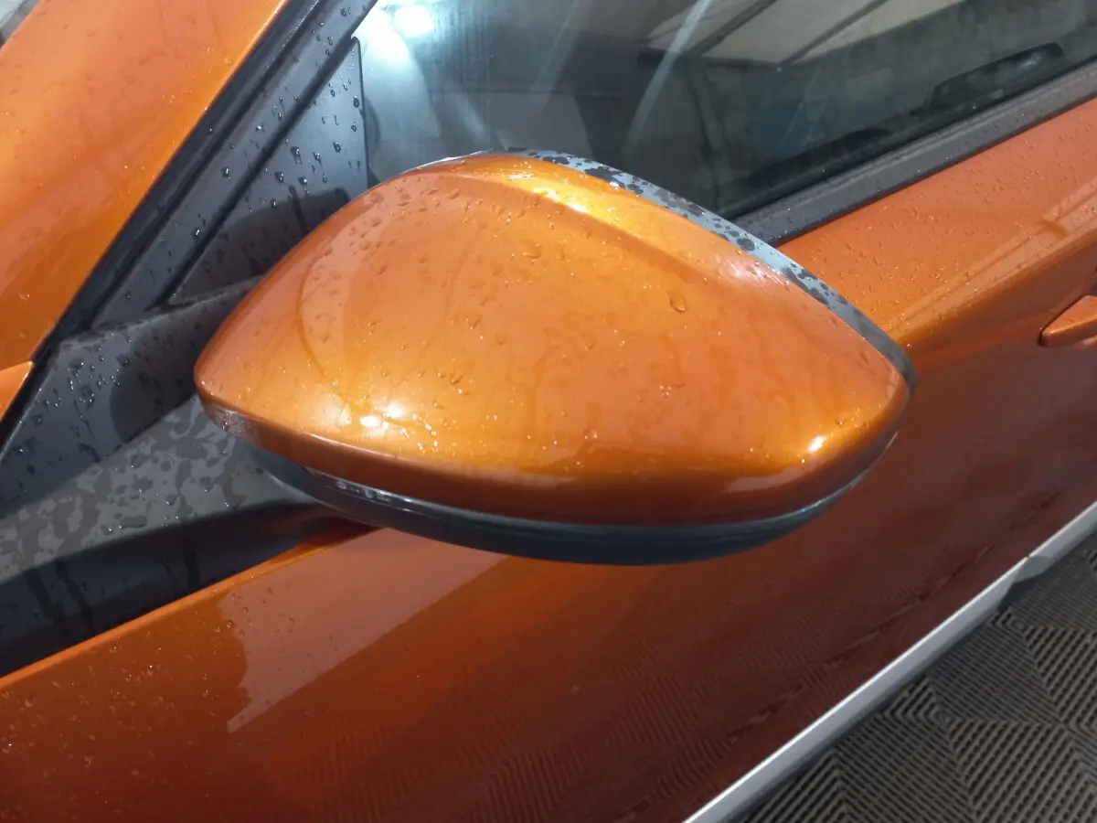 Rétroviseur côté gauche orange brillant de la Peugeot 2008 BlueHDi 110 S&S Allure Business 2021 avec gouttes d'eau visibles.