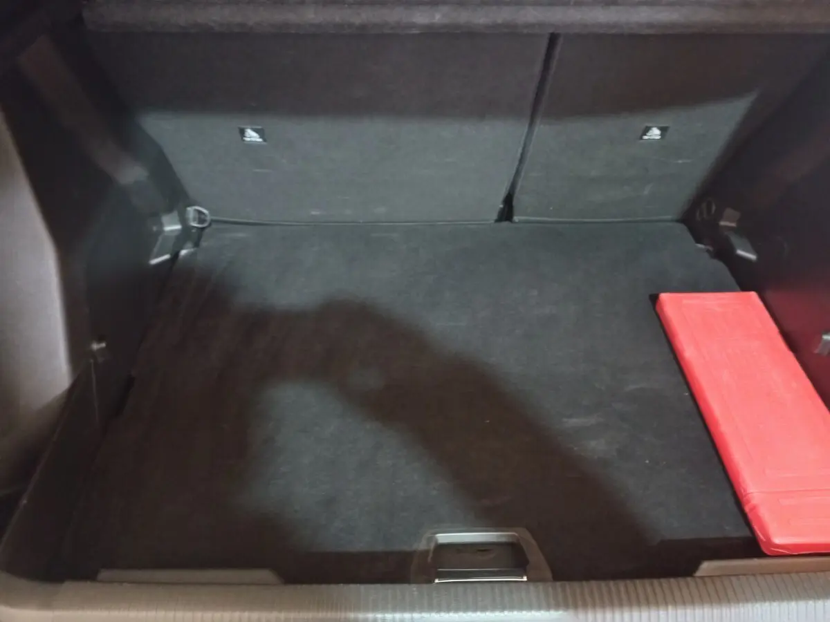 Coffre noir vu de face du Peugeot 2008 2021 avec un kit de sécurité rouge posé à droite.