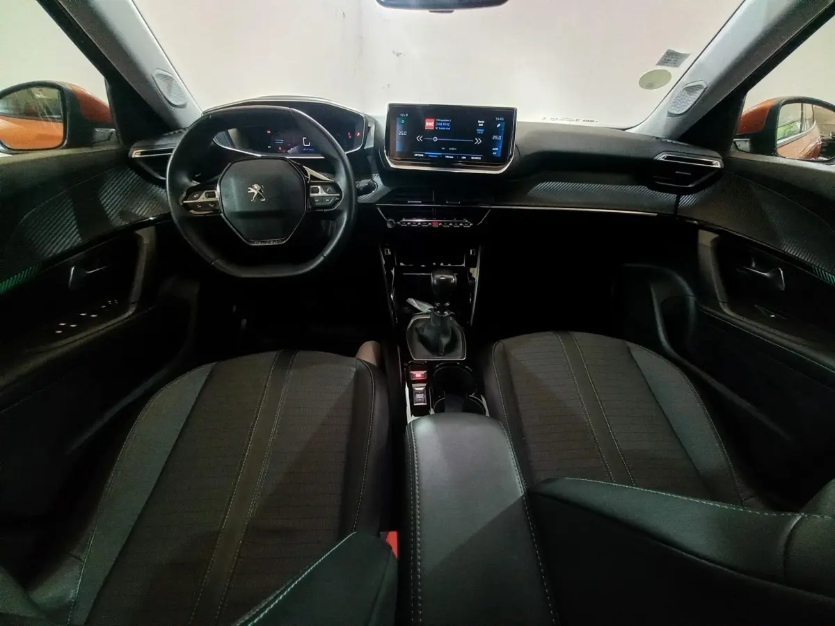 Intérieur du Peugeot 2008 orange 2021 vu de face, tableau de bord moderne avec écran tactile 10 pouces et volant cuir.