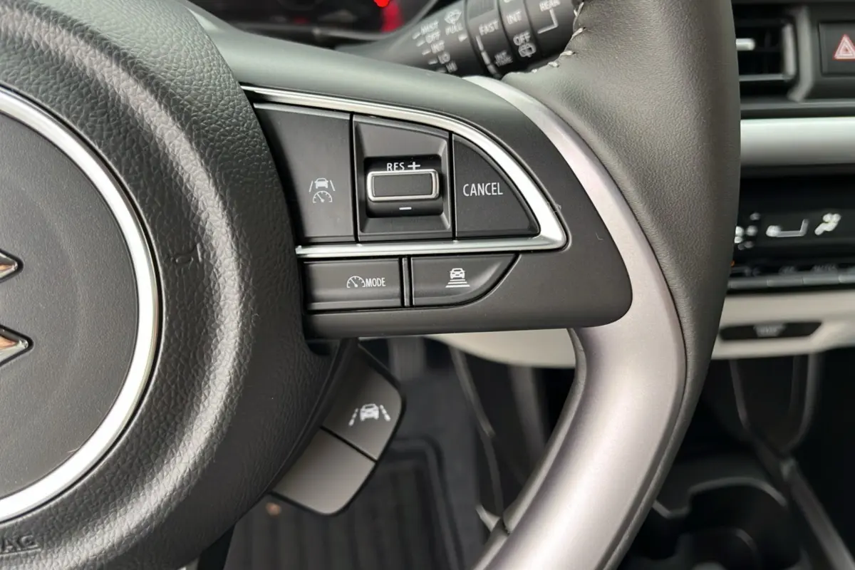 Gros plan sur le volant cuir multifonctions gris et ses commandes d’aide à la conduite de la Suzuki Swift 2026.