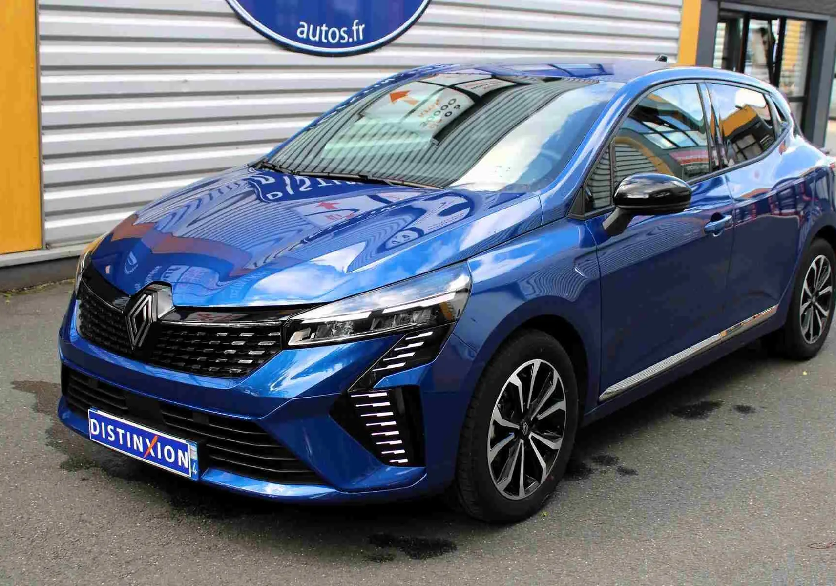 Renault Clio hybride bleu Iron Metal vue 3/4 avant droit, avec calandre noire et feux LED distinctifs.