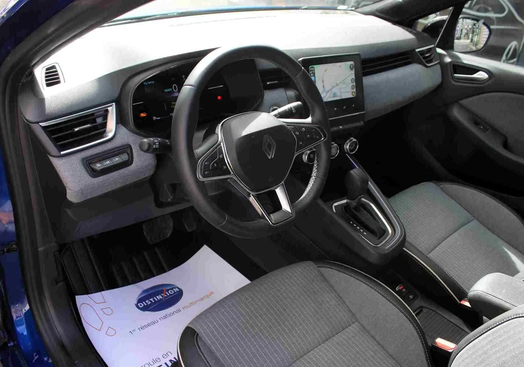 Coffre ouvert d’une Renault Clio bleu Iron Metal 2025, montrant la roue de secours et les outils de bord.