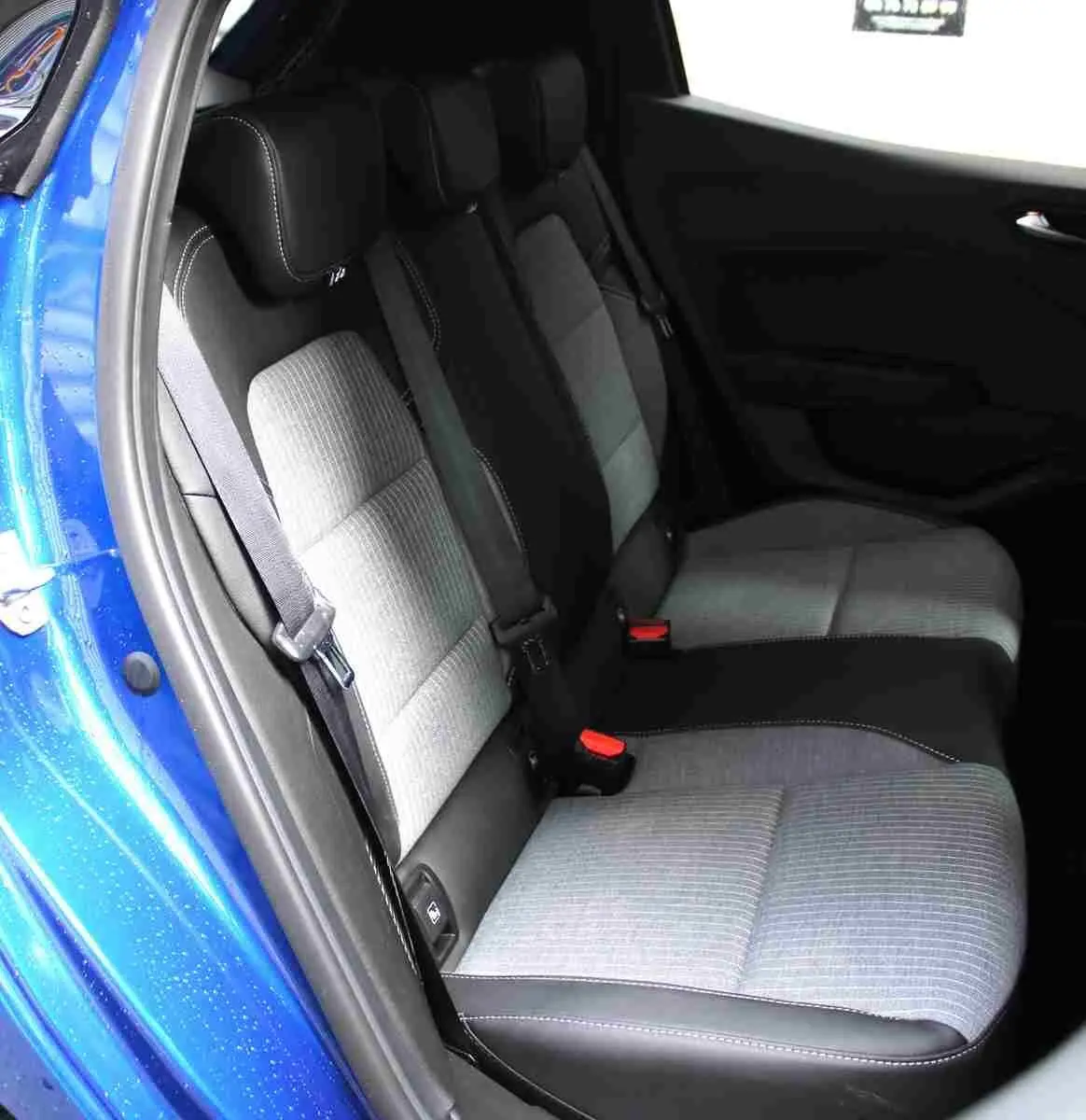 Vue intérieure côté arrière droit de la Renault Clio bleu Iron Metal, montrant les sièges arrière bi-matière gris clair et noir.