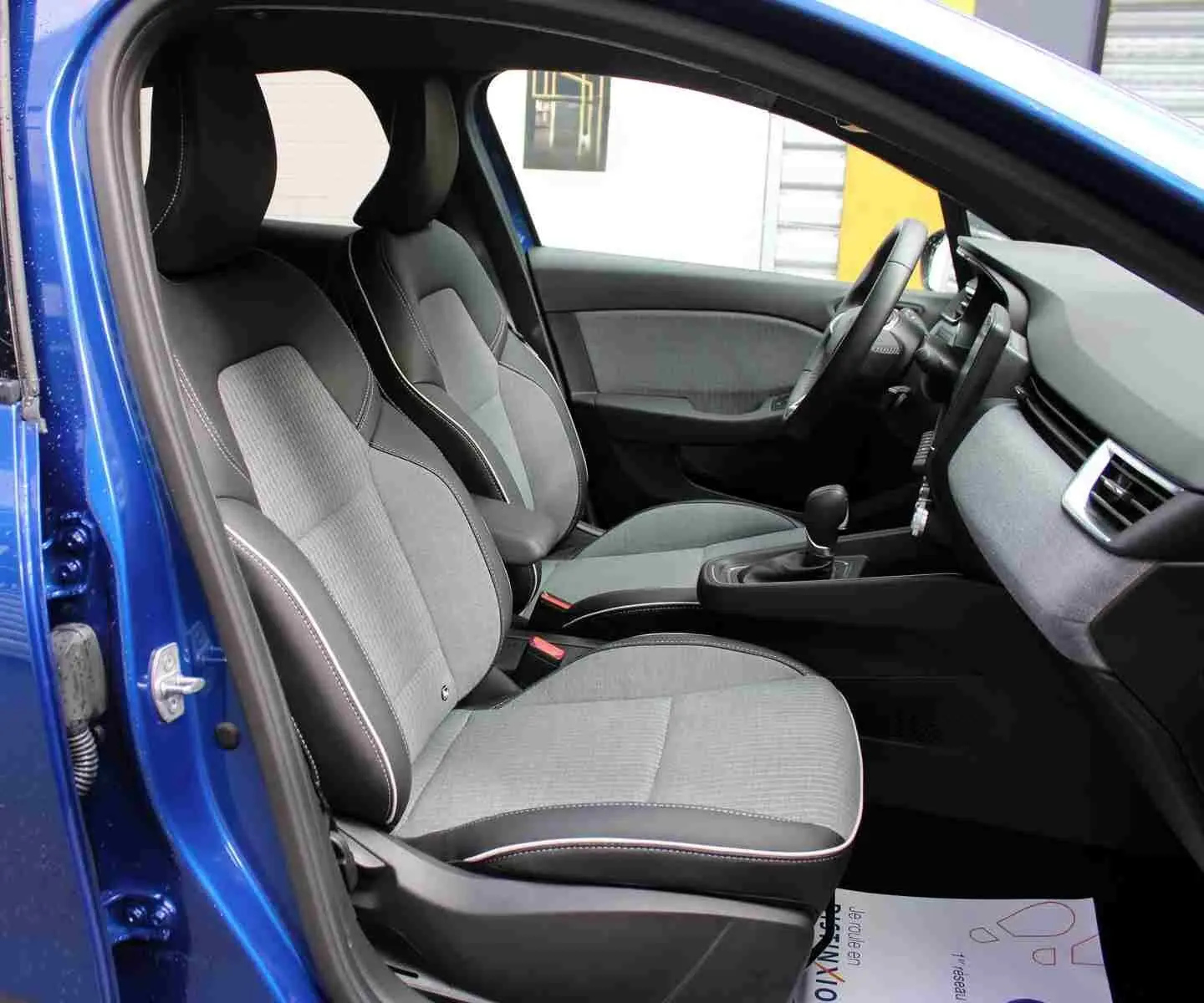Vue intérieure côté gauche des sièges arrière gris clair et noir d'une Renault Clio bleu iron metal 2025.