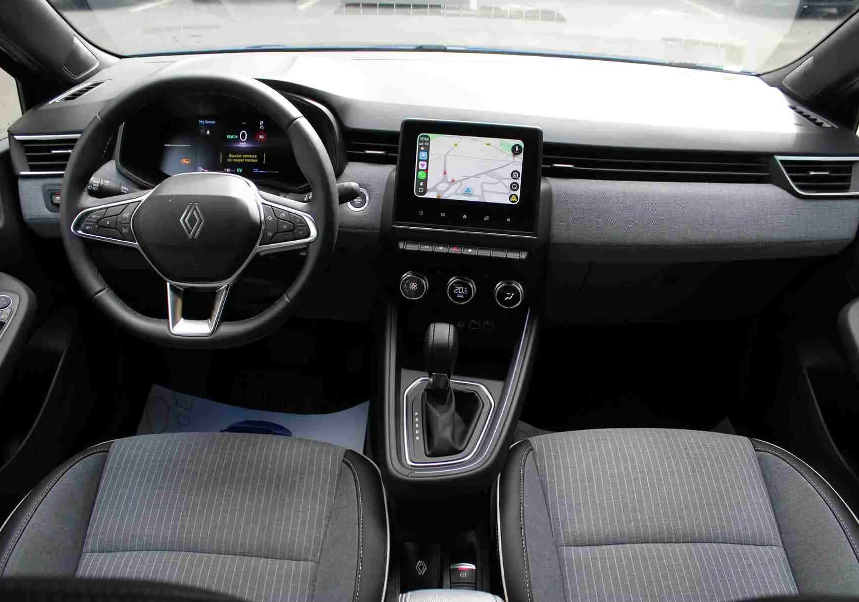 Vue intérieure côté gauche de la Renault Clio 2025 bleu iron metal, montrant les sièges avant gris et noir avec surpiqûres blanches.
