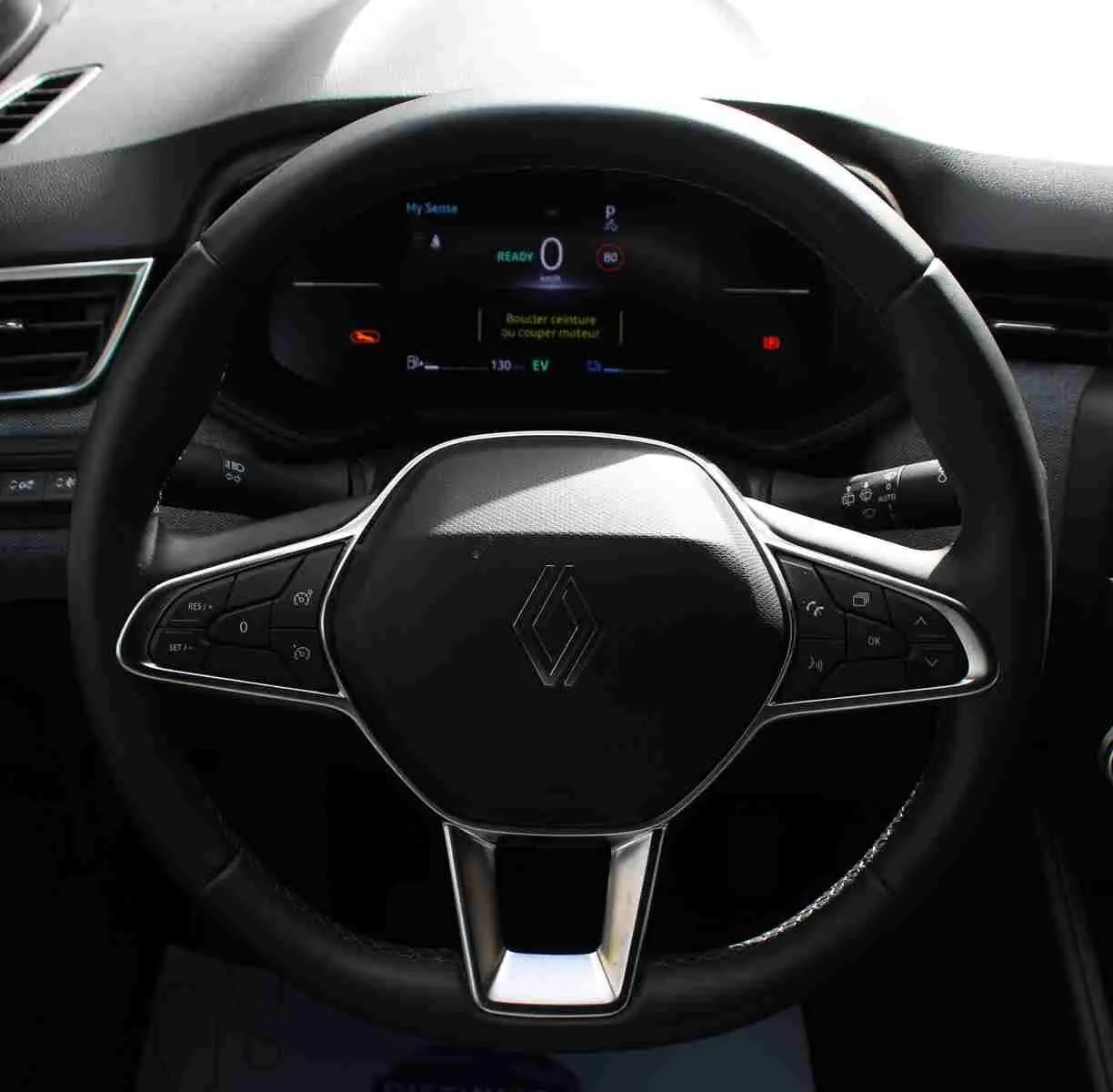 Vue rapprochée du volant noir de la Renault Clio hybride 2025 avec commandes intégrées et tableau de bord numérique.