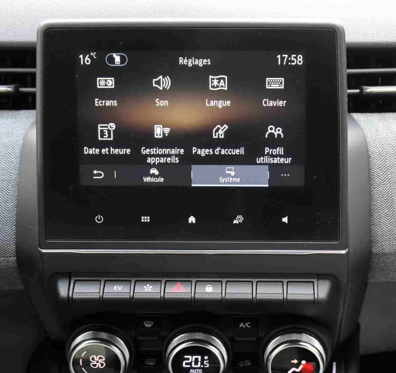 Écran tactile central affichant les réglages du système dans l'habitacle gris-noir de la Renault Clio hybride 2025.