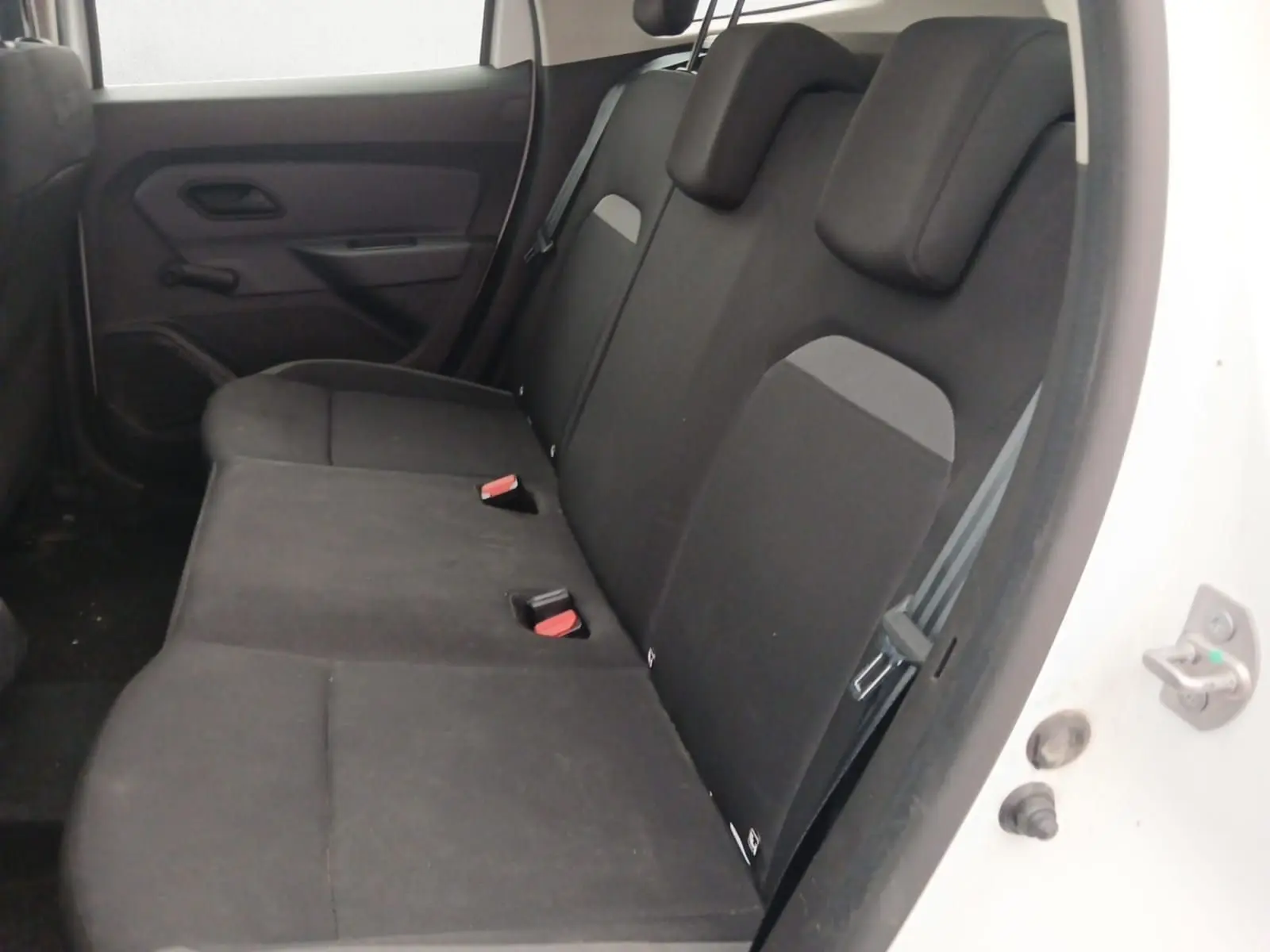 Vue intérieure côté arrière droit du Dacia Duster blanc 2021, montrant la banquette arrière en tissu noir avec appuie-têtes.